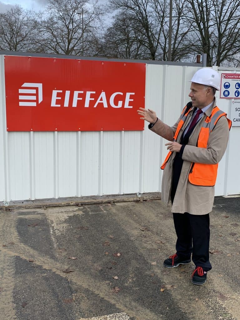 Laurent Delporte en visite de chantier hôtelier, casque et gilet de sécurité, devant un panneau Eiffage