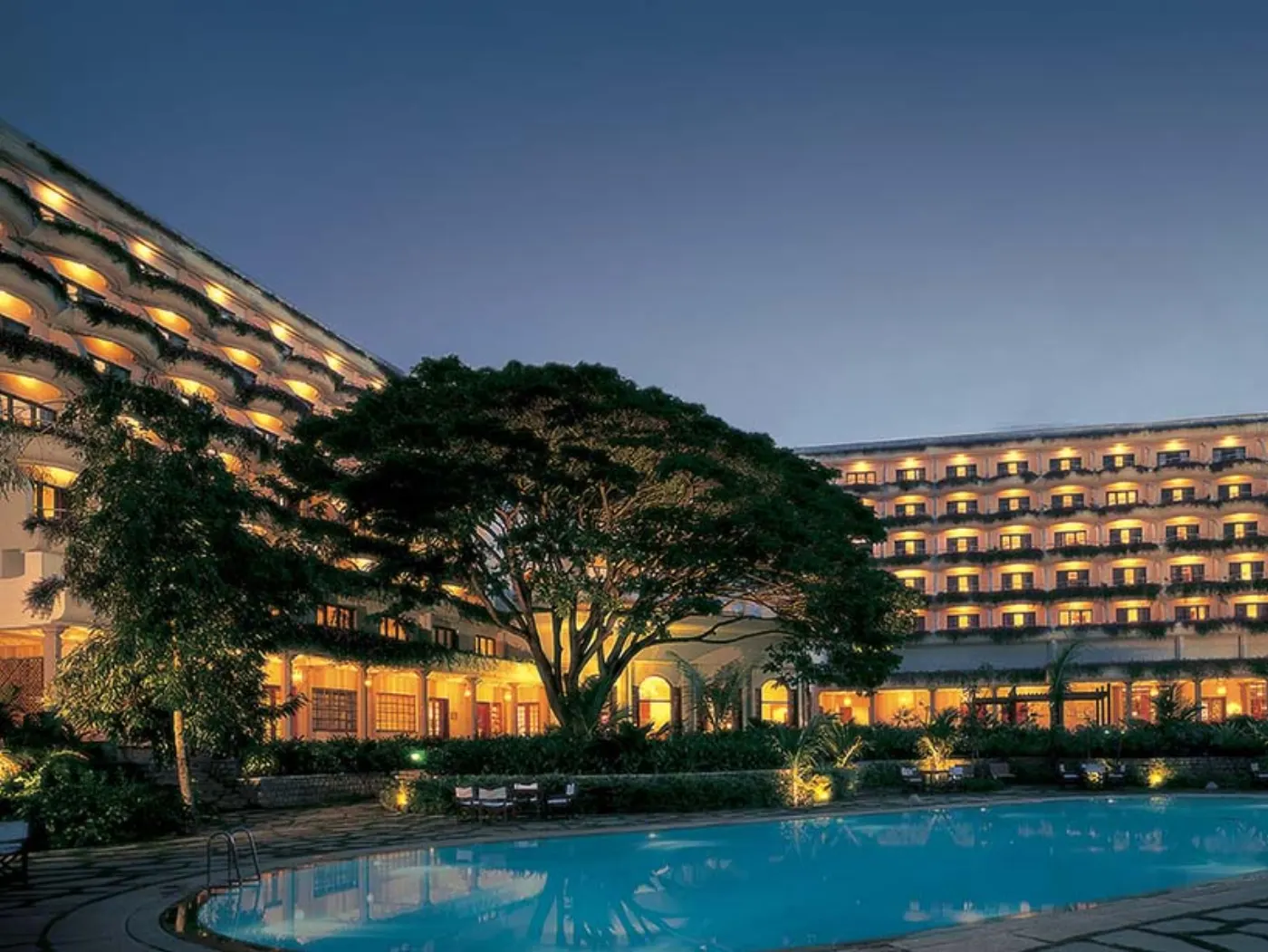 Hôtel Oberoi illuminé à la nuit tombée, ses balcons de verdure en arc de cercle autour de la piscine