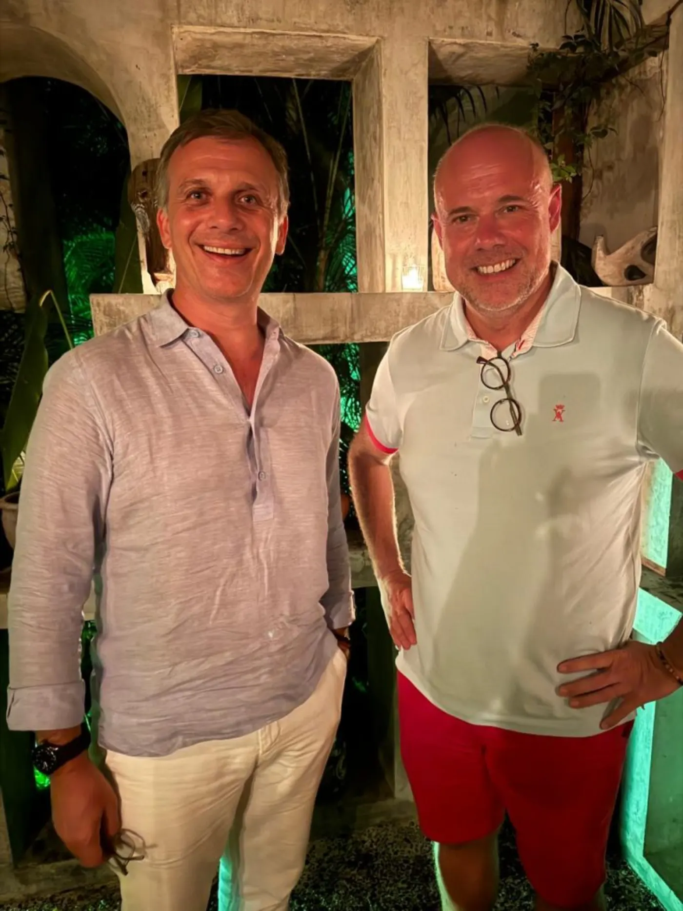 Laurent Delporte et un hôtelier lors d'une soirée en extérieur, dans un décor tropical illuminé