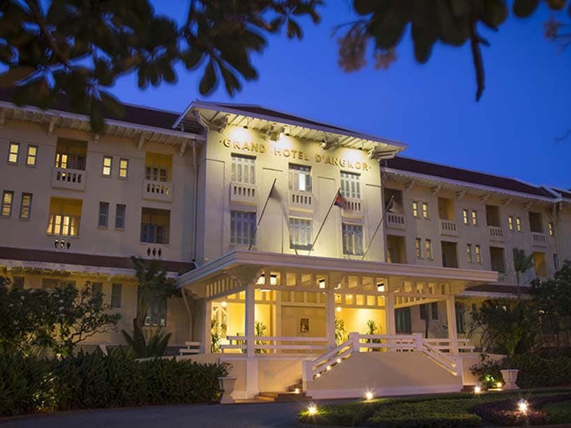 The Grand Hotel d'Angkor lit at dusk, its white porch steps and golden sign