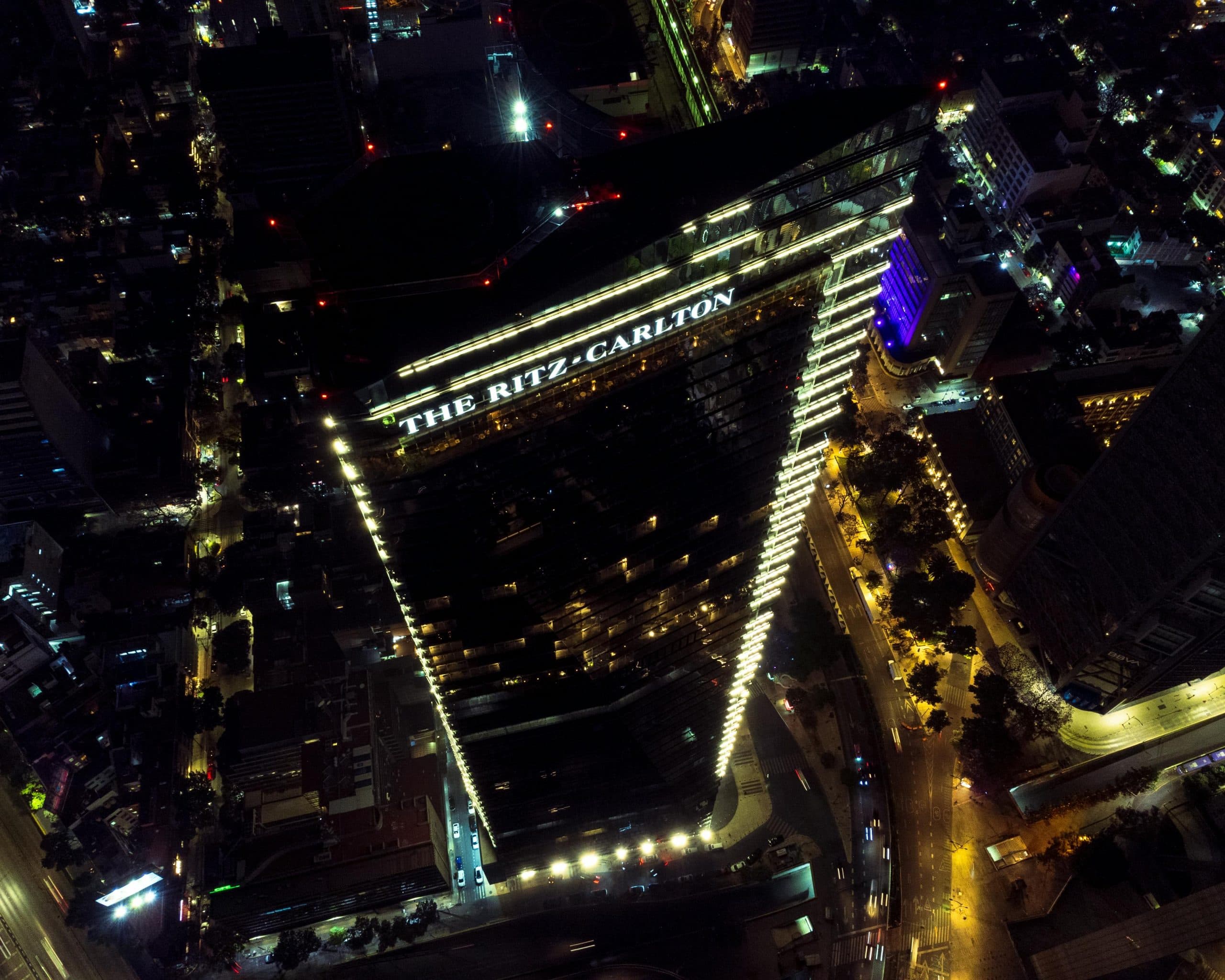 Tour Ritz-Carlton vue du ciel la nuit, son enseigne lumineuse dominant les avenues éclairées
