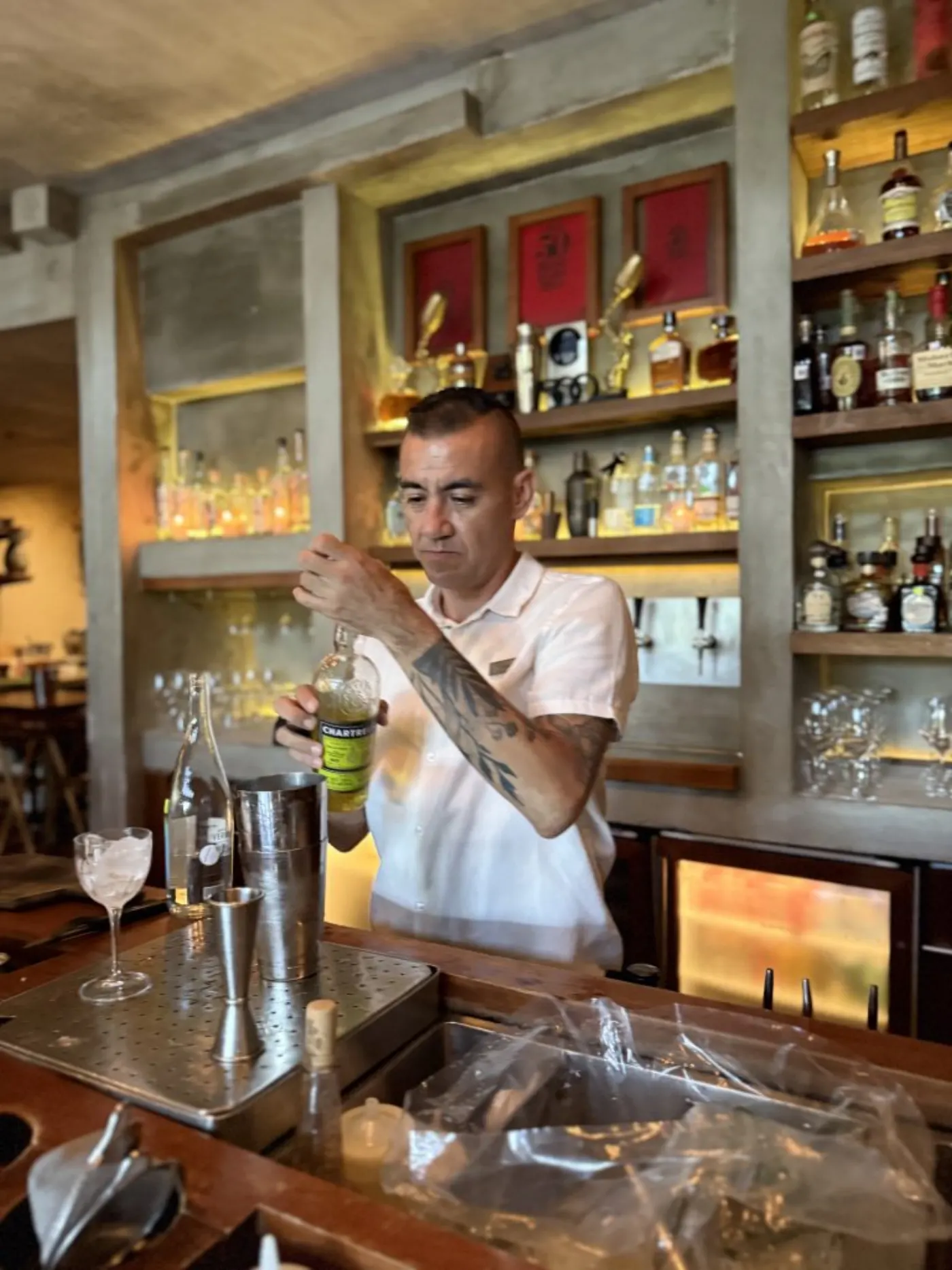 Le barman du Zapote Bar dosant une liqueur Chartreuse, shaker et verre à mesurer sur le comptoir