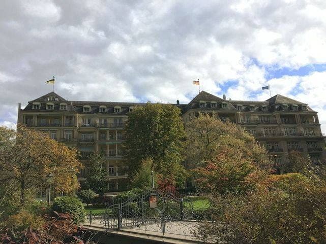 Brenners Park-Hotel & Spa à Baden-Baden vu du parc, sa façade et ses drapeaux derrière les arbres d'automne