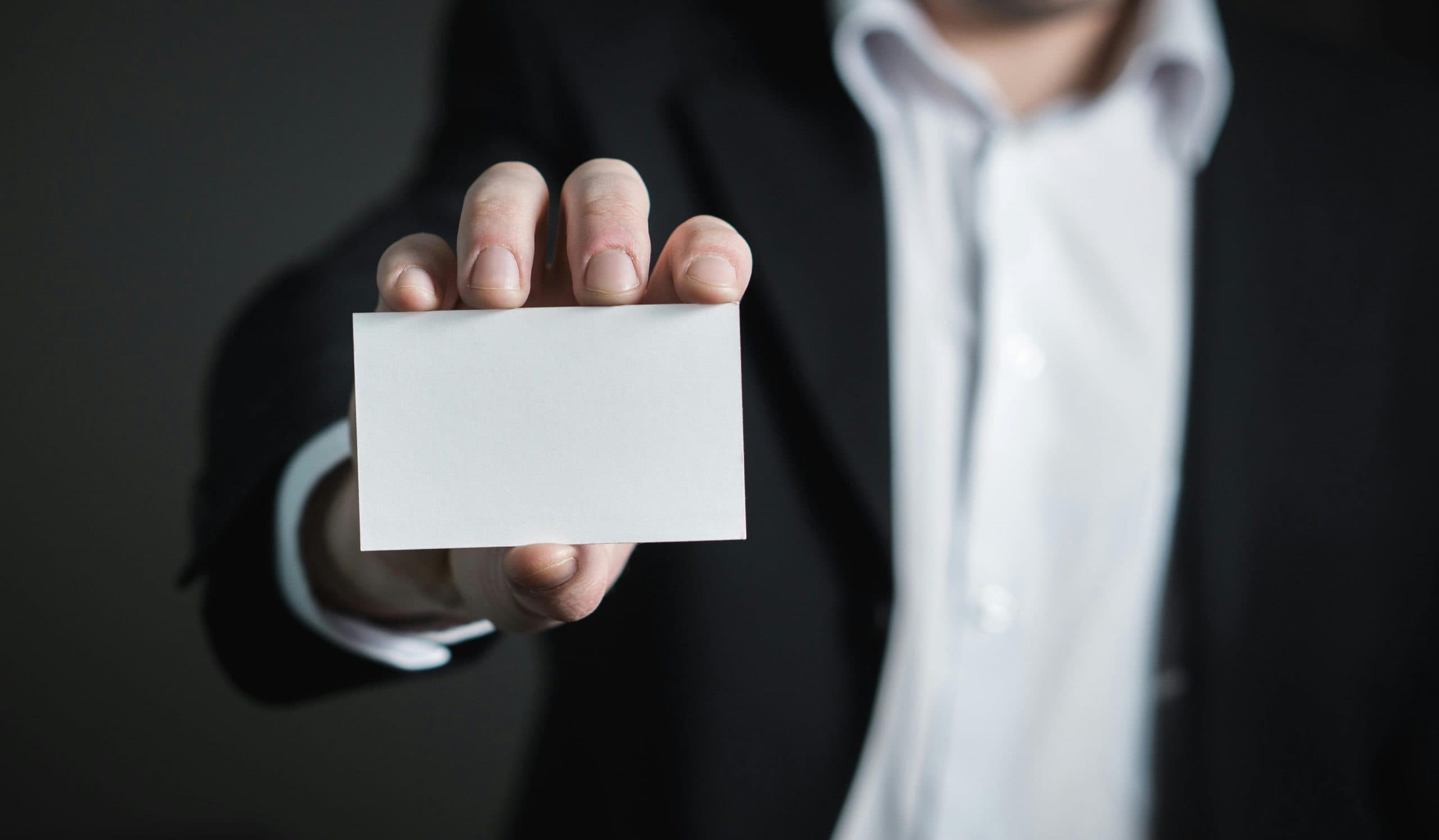 Homme en costume tendant une carte blanche vierge vers l'objectif
