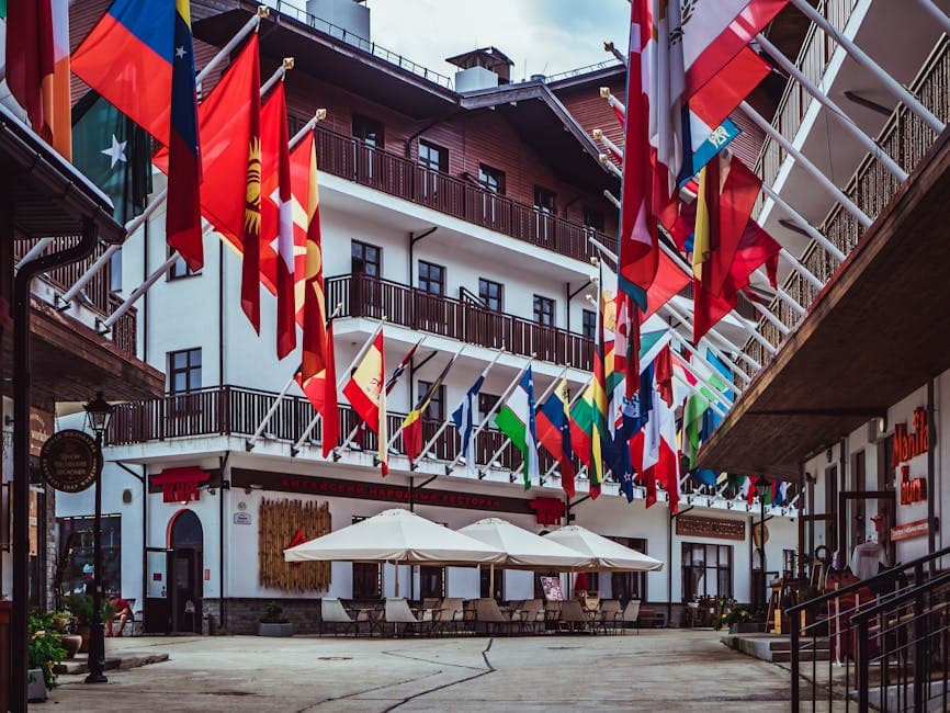Cour d'hôtel bordée de dizaines de drapeaux nationaux, tables et parasols au centre
