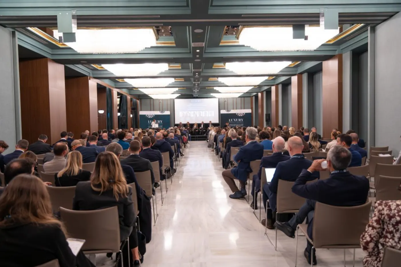 Salle de conférence comble vue depuis le fond, public en costume face à la scène de la Luxury Hospitality Conference