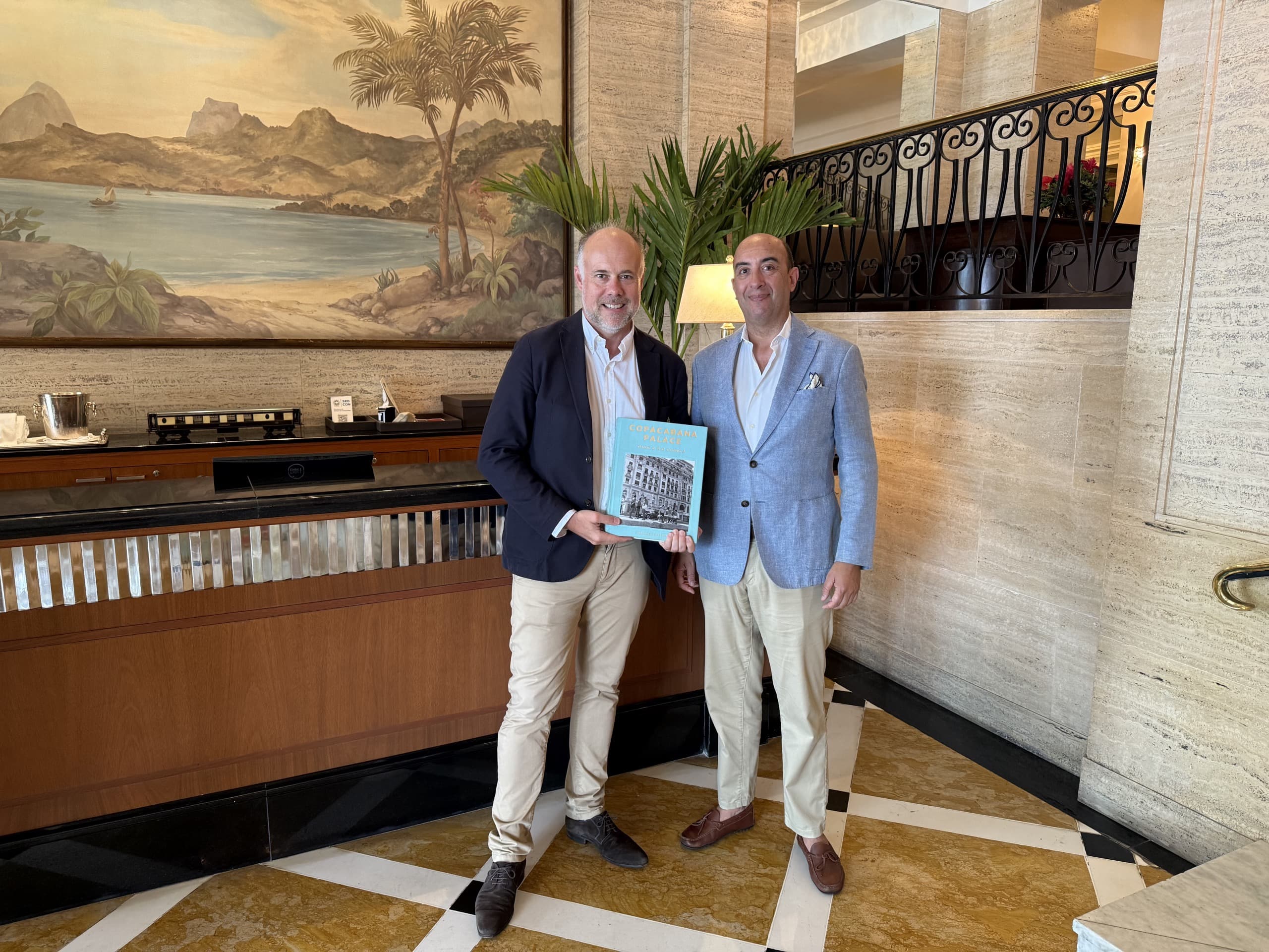 Laurent Delporte et Ulisses Marreiros, directeur général du Copacabana Palace, tenant le livre de l'hôtel dans le hall