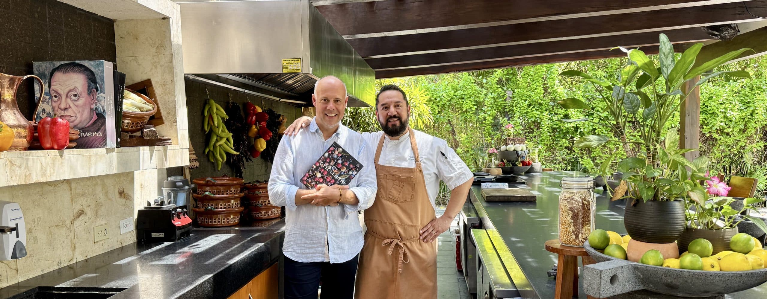 Laurent Delporte et le chef Edgar Chávez dans la cuisine ouverte du Rosewood Mayakoba, livre de cuisine en main