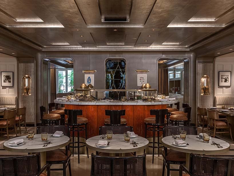 Restaurant de l'Hôtel de Crillon : comptoir central en bois, tables de marbre et plafond métallisé