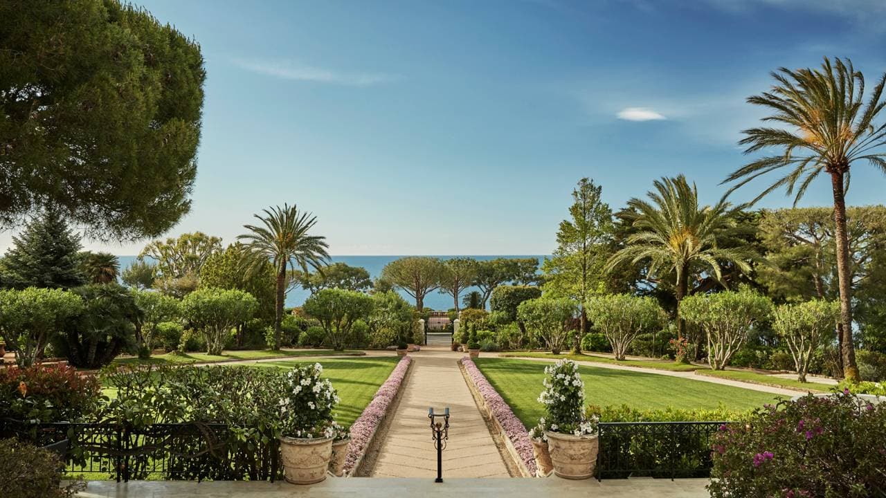 Allée fleurie du Grand-Hôtel du Cap-Ferrat descendant vers la mer entre pelouses et palmiers