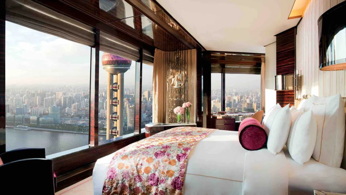 Chambre Art déco face à la Perle de l'Orient, couvre-lit fleuri, traversin rose et vue sur le Huangpu