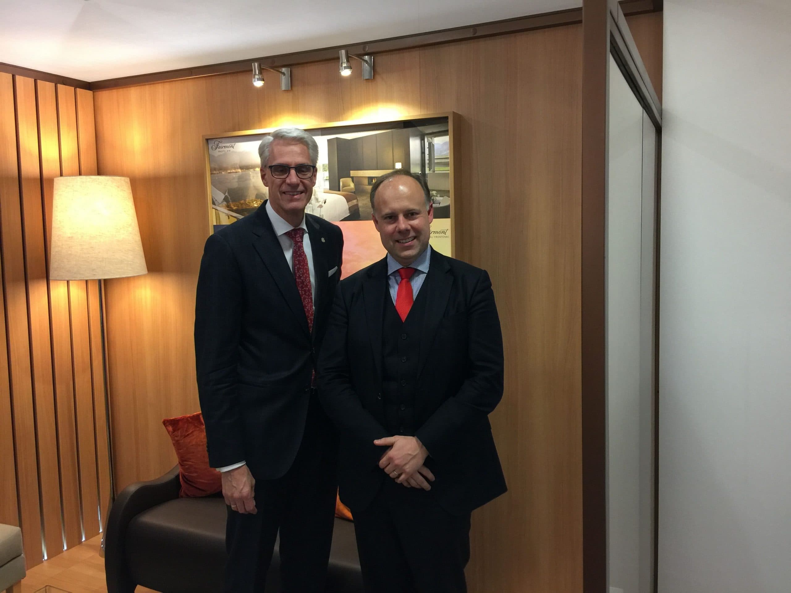 Laurent Delporte et un directeur d'hôtel devant un panneau Fairmont, lors d'un salon professionnel