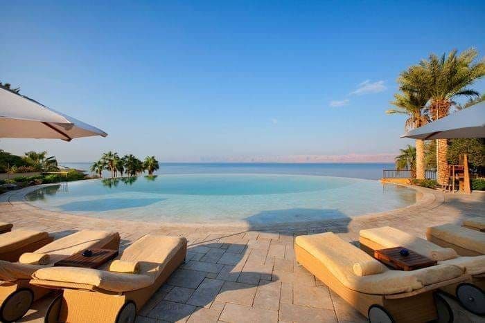 Piscine à débordement du Kempinski Ishtar face à la mer Morte, transats et palmiers