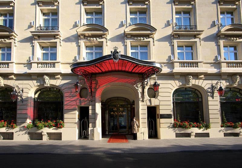 Entrée du Peninsula Paris : la marquise rouge, les lanternes et les jardinières de géraniums
