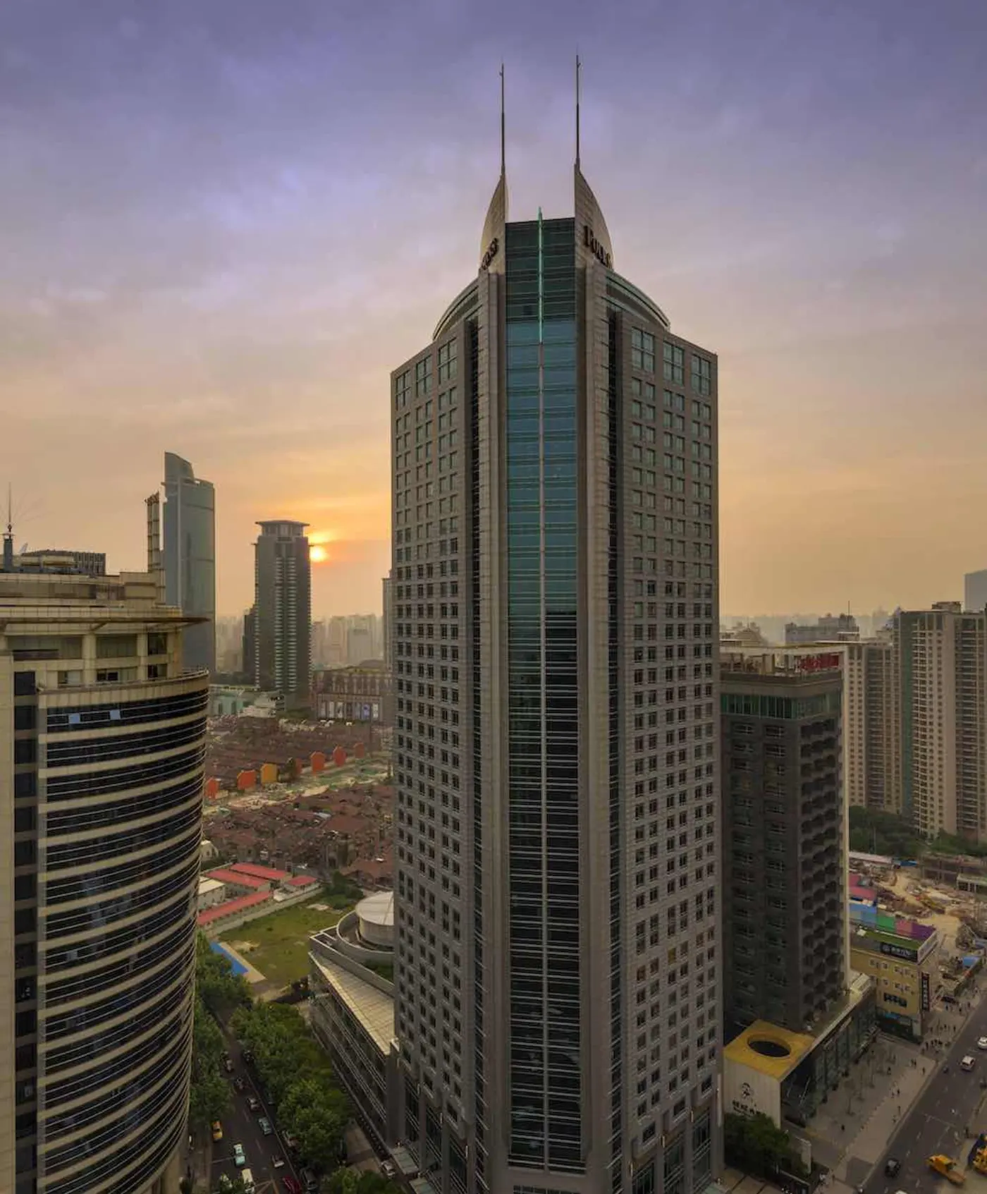 Tour du Four Seasons Shanghai et ses deux flèches au coucher du soleil, dominant les toits de la ville
