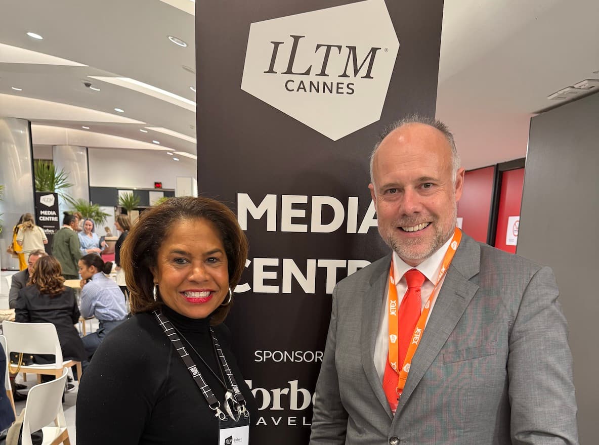 Laurent Delporte and a fellow journalist at the ILTM Cannes Media Centre, beside the event banner