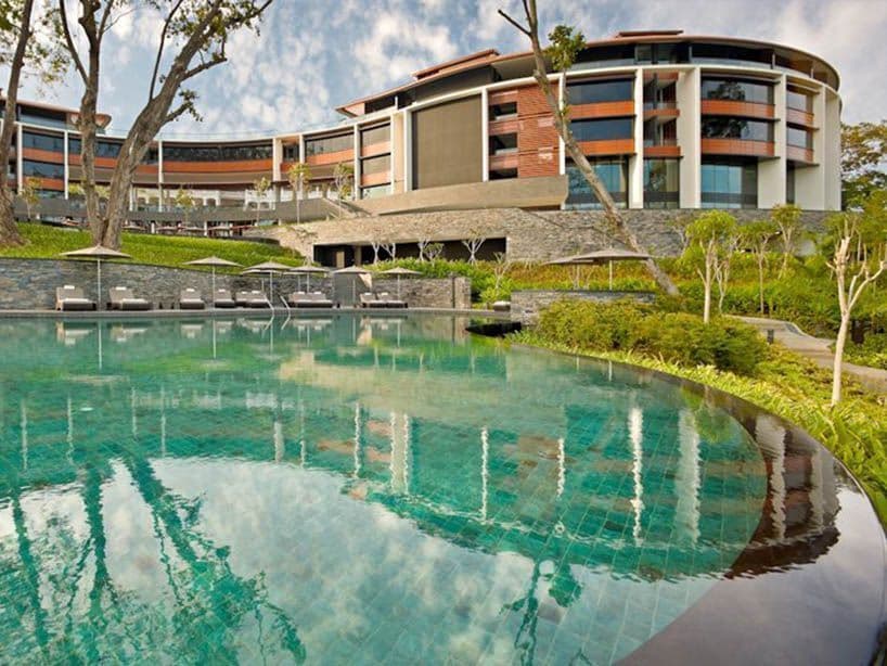 Resort Capella aux façades incurvées, sa piscine turquoise et ses transats sous les parasols