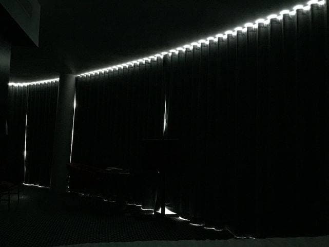 Chambre plongée dans le noir, un filet de lumière filtrant sur toute la longueur des rideaux occultants