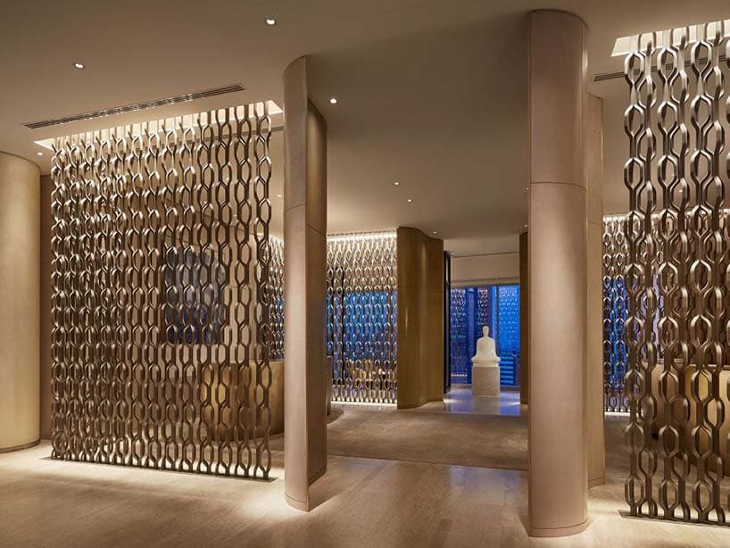 Hall du Park Hyatt Bangkok : claustras de laiton ajourés, colonnes claires et sculpture blanche au fond