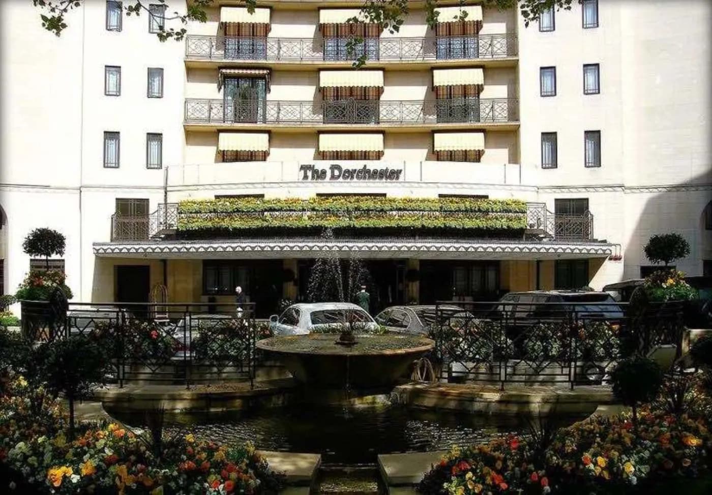 Façade du Dorchester à Londres, fontaine et massifs fleuris devant l'auvent de l'entrée principale