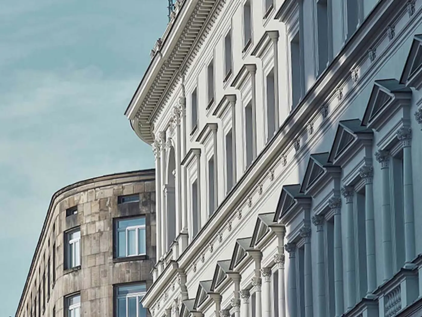 Façades néoclassiques vues en contre-plongée, colonnes et frontons blancs se détachant sur un ciel bleu