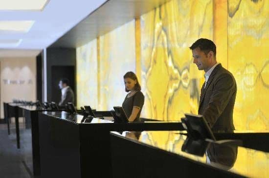 Trois réceptionnistes à leur comptoir devant un mur d'onyx jaune rétroéclairé