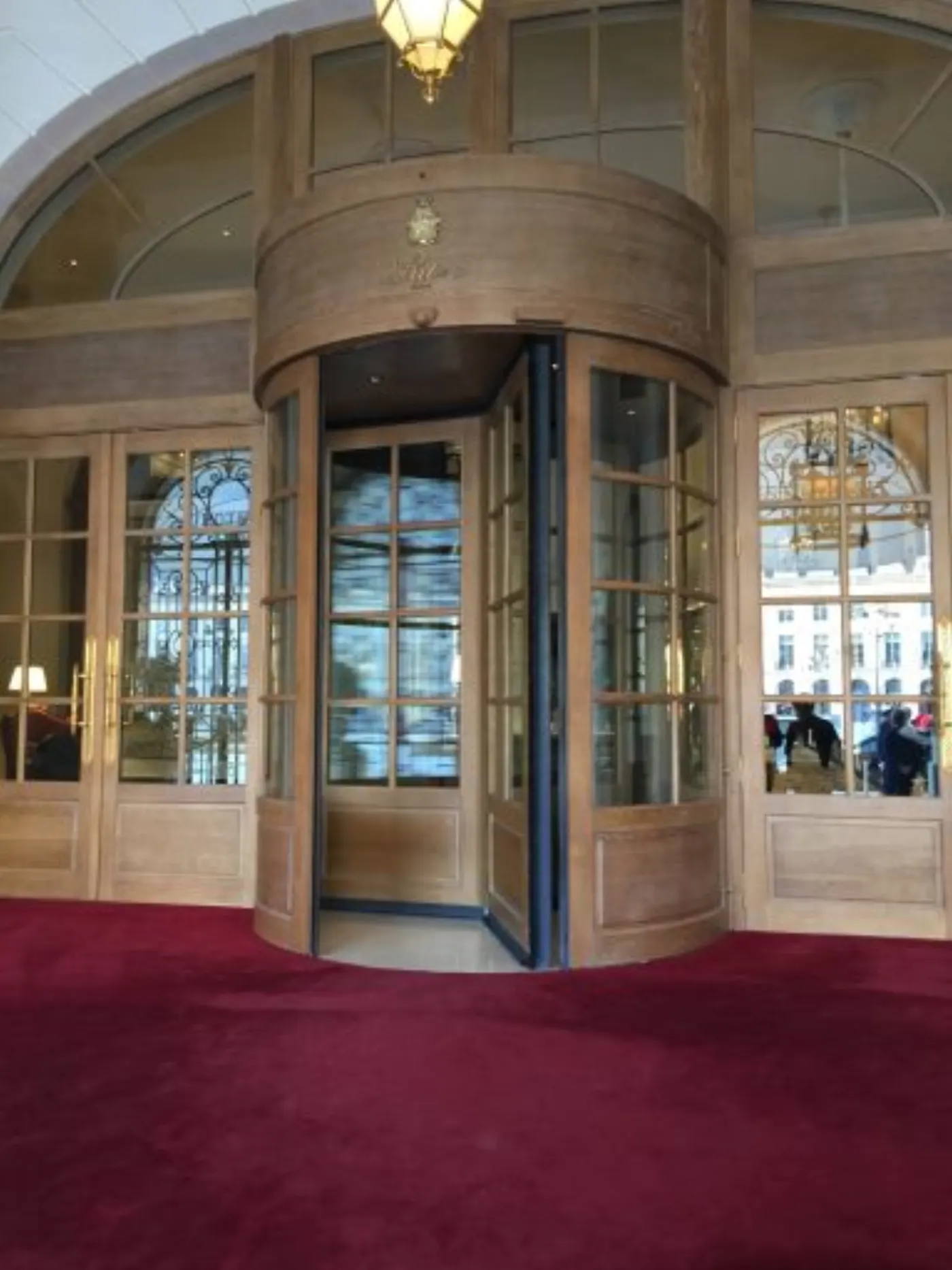 Porte à tambour en bois du Ritz Paris vue de l'intérieur, tapis rouge et place Vendôme au dehors