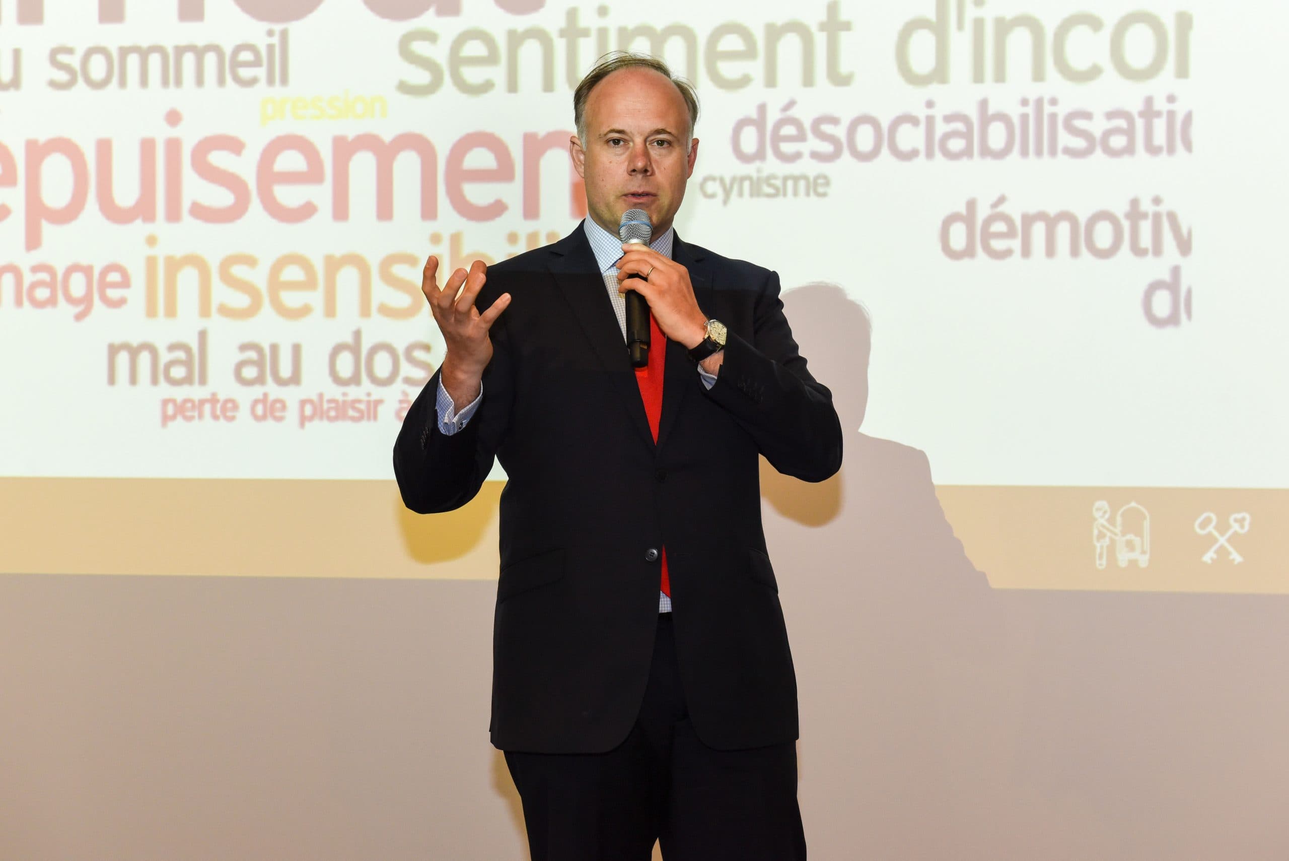 Laurent Delporte au micro devant un écran de mots : épuisement, pression, désociabilisation, démotivation