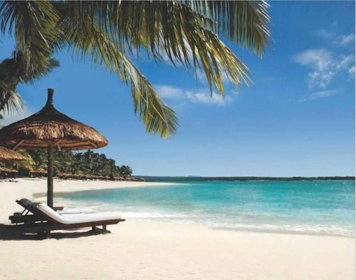 Transats sous un parasol de paille sur une plage de sable blanc bordée d'un lagon turquoise, à l'île Maurice