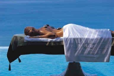 Table de massage dressée au bord d'un bassin, la mer bleue à perte de vue en arrière-plan