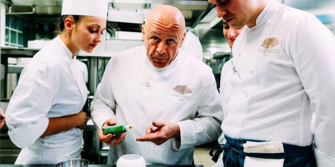 Le chef Thierry Marx en cuisine au Mandarin Oriental Paris, expliquant un geste à trois jeunes cuisiniers