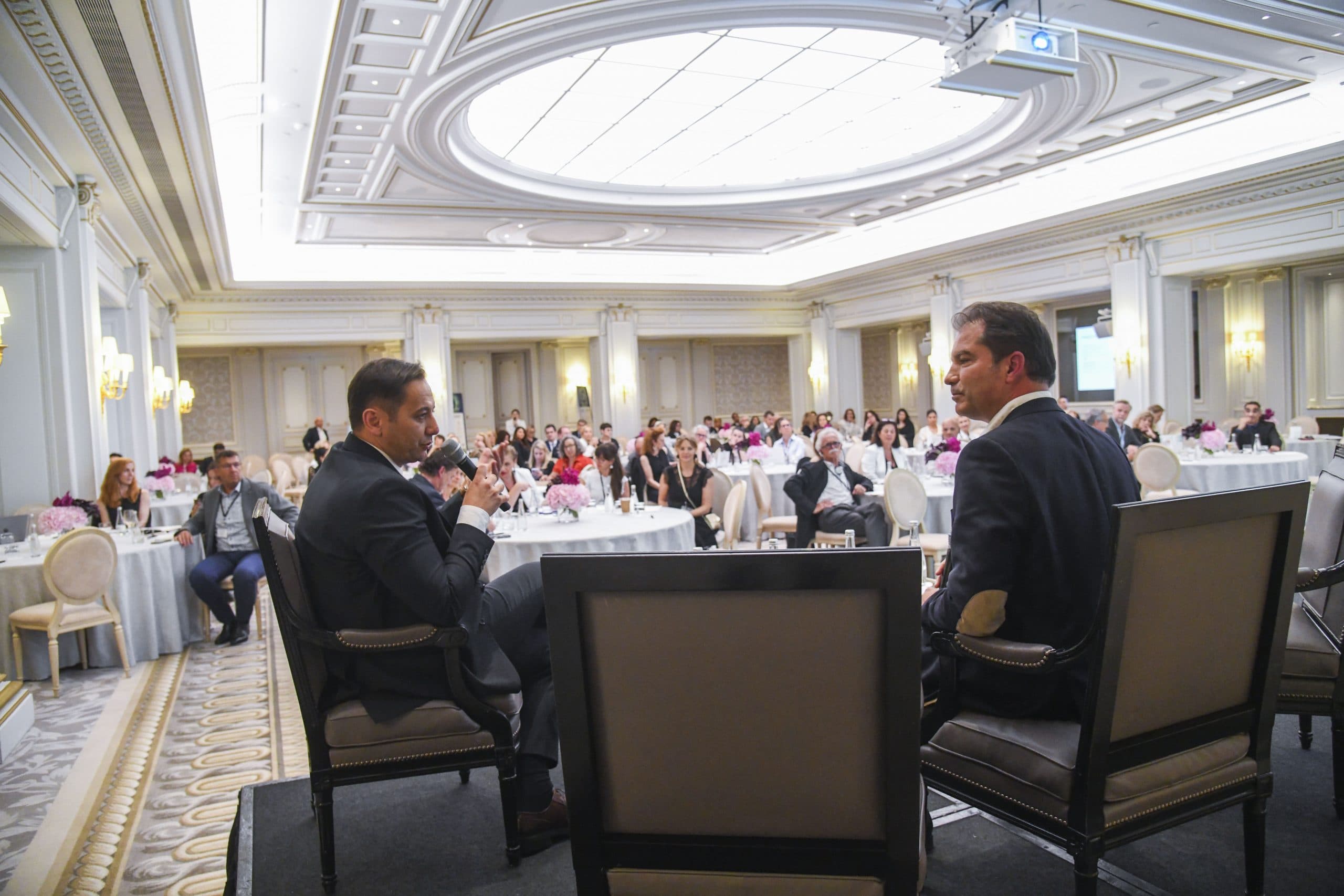 Forum Hotel&Spa panel in a palace ballroom, two speakers at the microphone facing the audience