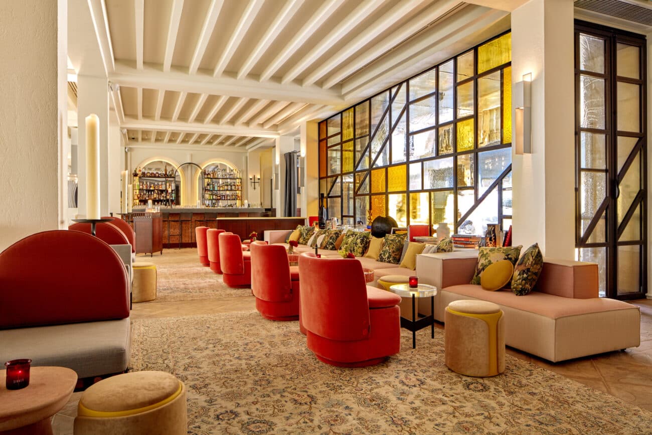 Hotel lounge with red velvet armchairs, yellow stained glass and the bar behind