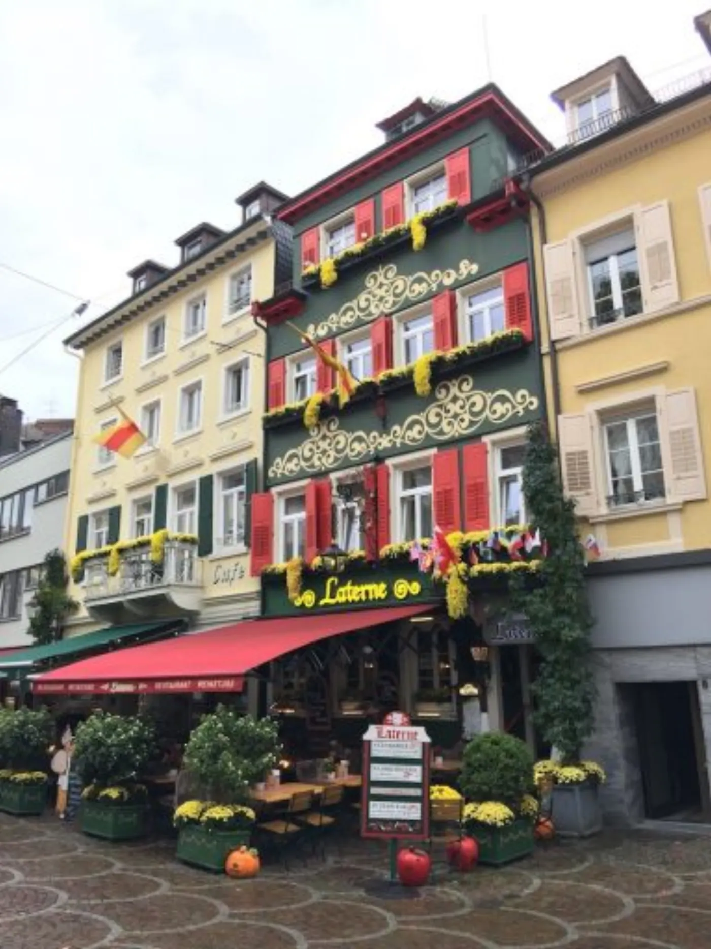 Façade verte du restaurant Laterne à Baden-Baden, ses volets rouges et ses chrysanthèmes jaunes