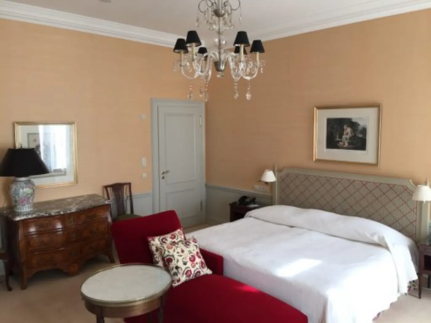 Chambre du Brenners Park-Hotel : commode marquetée, lustre à abat-jour noirs et fauteuil rouge