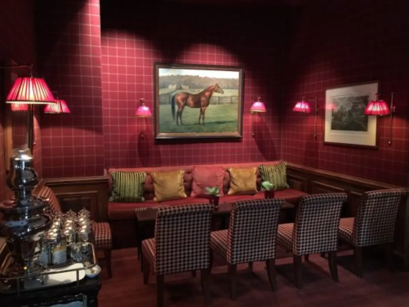 Salon feutré aux murs bordeaux, portrait de cheval et samovar d'argent sur la desserte