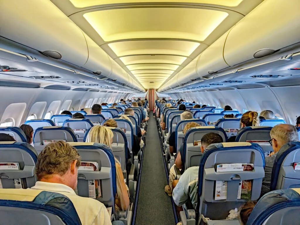 Cabine d'avion vue de l'arrière : rangées de sièges bleus occupées par les passagers