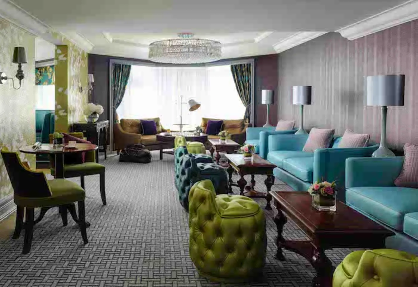 Salon d'hôtel au lustre en cristal, canapés turquoise, fauteuils capitonnés vert anis et moquette à motifs