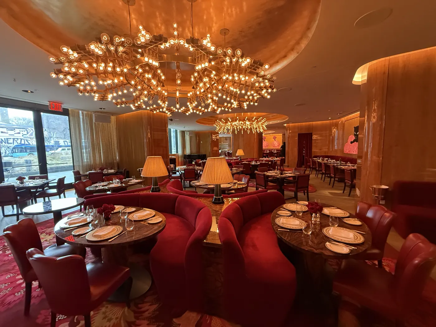 Salle de restaurant du Faena New York : banquettes de velours rouge, plafond doré et immense lustre à ampoules