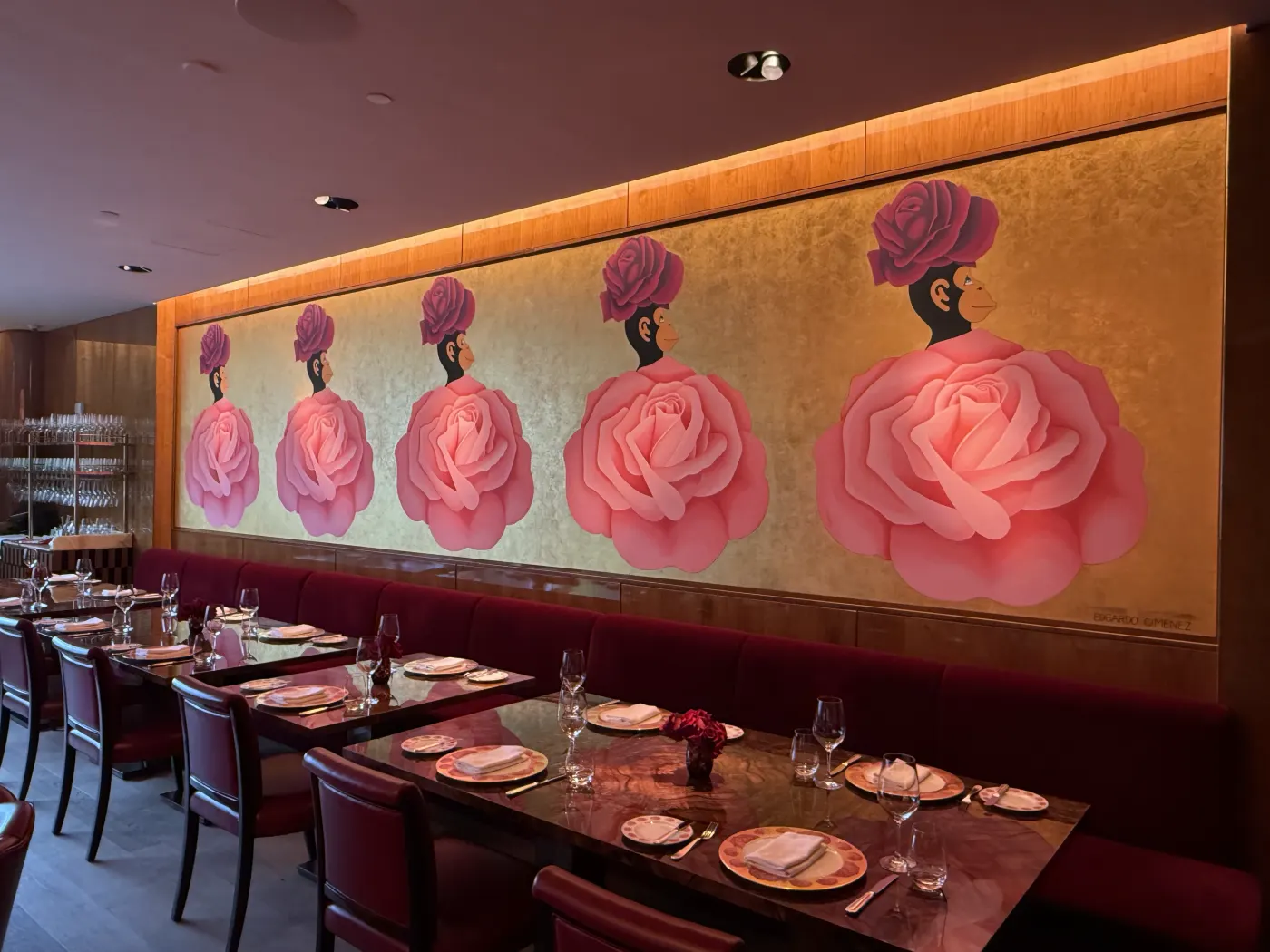Fresque murale sur fond d'or : cinq femmes coiffées de roses au-dessus d'une banquette rouge et de tables dressées