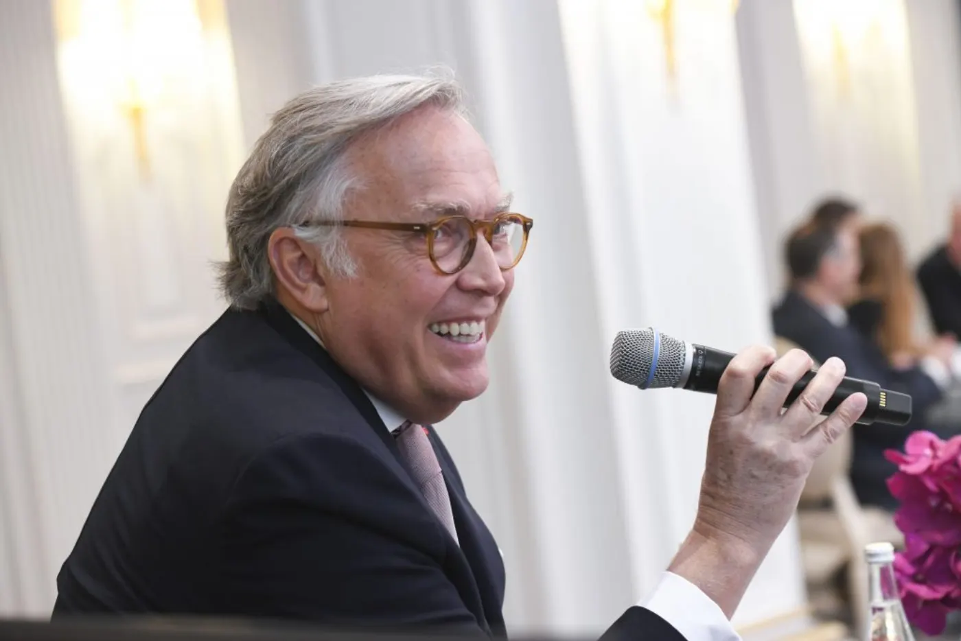 François Delahaye, lunettes d'écaille et costume sombre, micro à la main lors d'une prise de parole