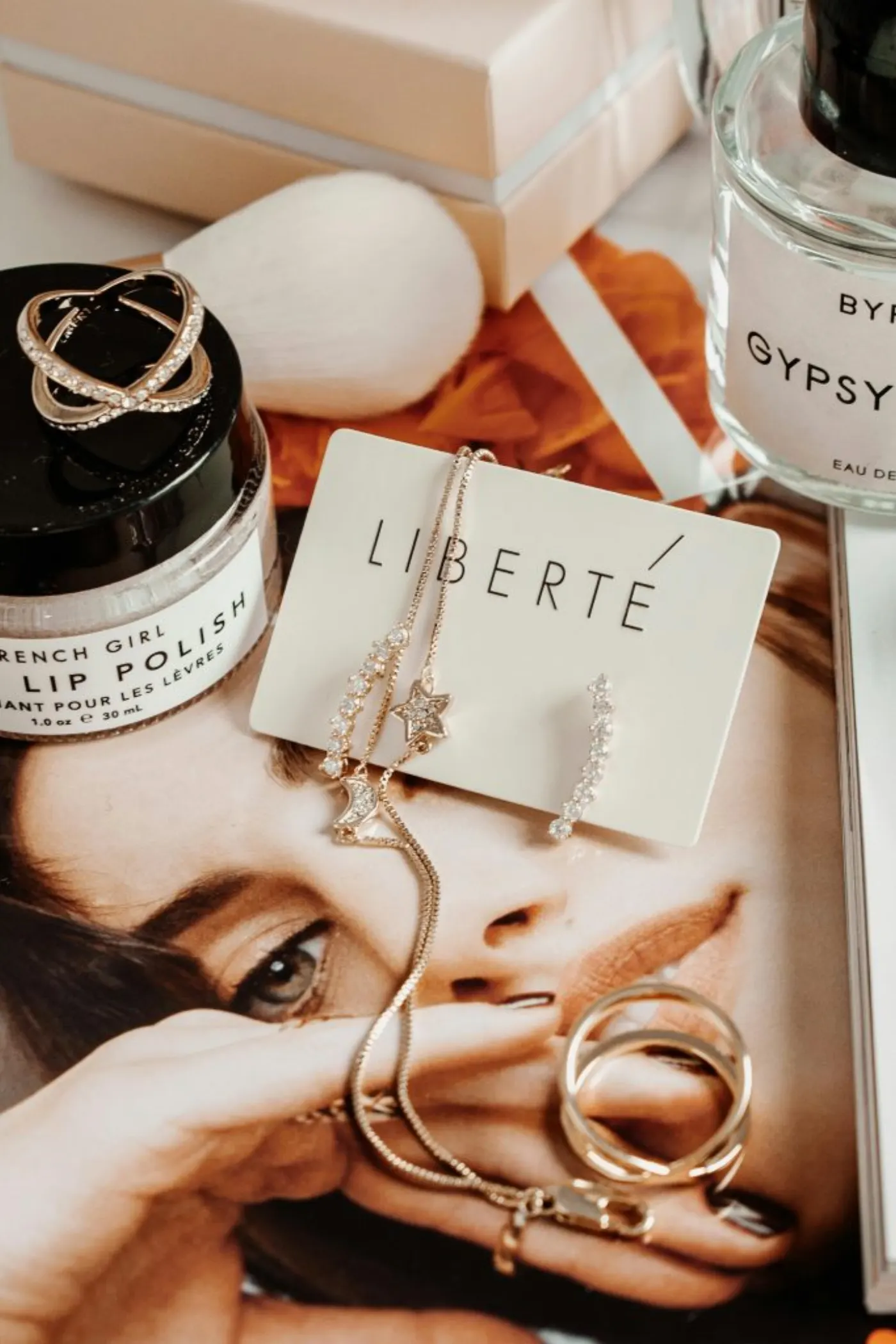 Close-up of jewelry, cosmetics, and fashion accessories arranged on a magazine with a luxury theme.