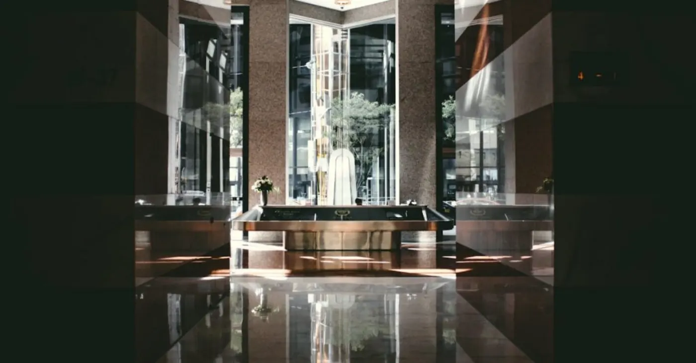 A sophisticated modern hotel lobby with glossy floors and natural light entering through large windows.