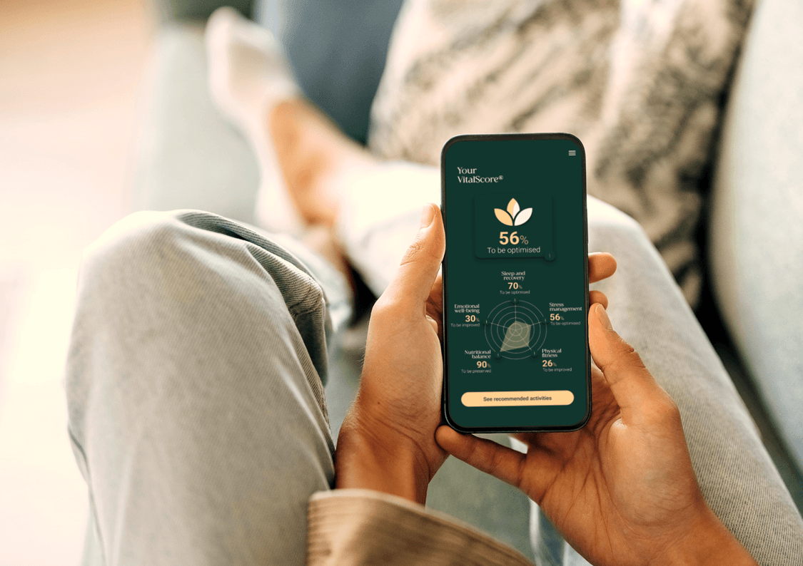 Application VitalScore affichée sur un téléphone tenu à deux mains : score de 56 % et roue du bien-être