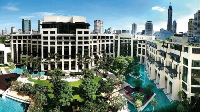 Aerial view of a Kempinski hotel complex: pools, tropical gardens and city towers beyond