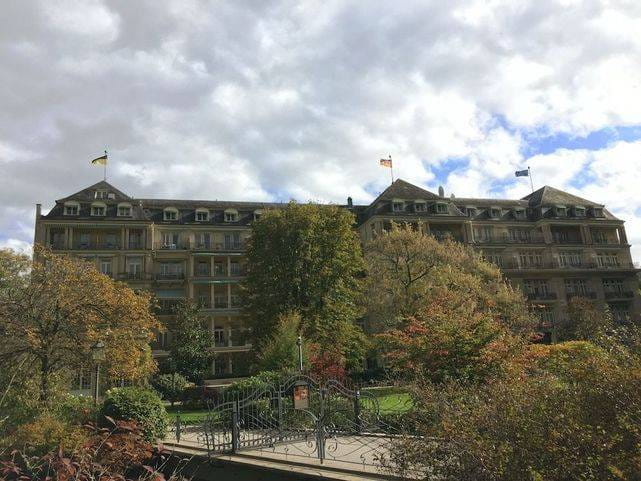 Brenners Park-Hotel & Spa à Baden-Baden vu du parc, sa façade et ses drapeaux derrière les arbres d'automne