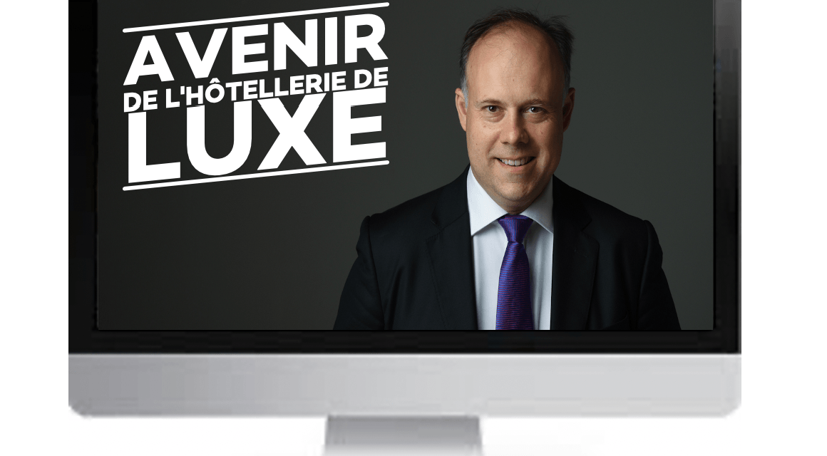 A filmed interview on screen, titled Avenir de l'hotellerie de luxe, showing the guest in a suit and striped tie