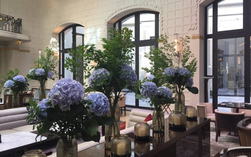 Salon du Lutetia orné de hautes compositions d'hortensias bleus, sous les moulures blanches