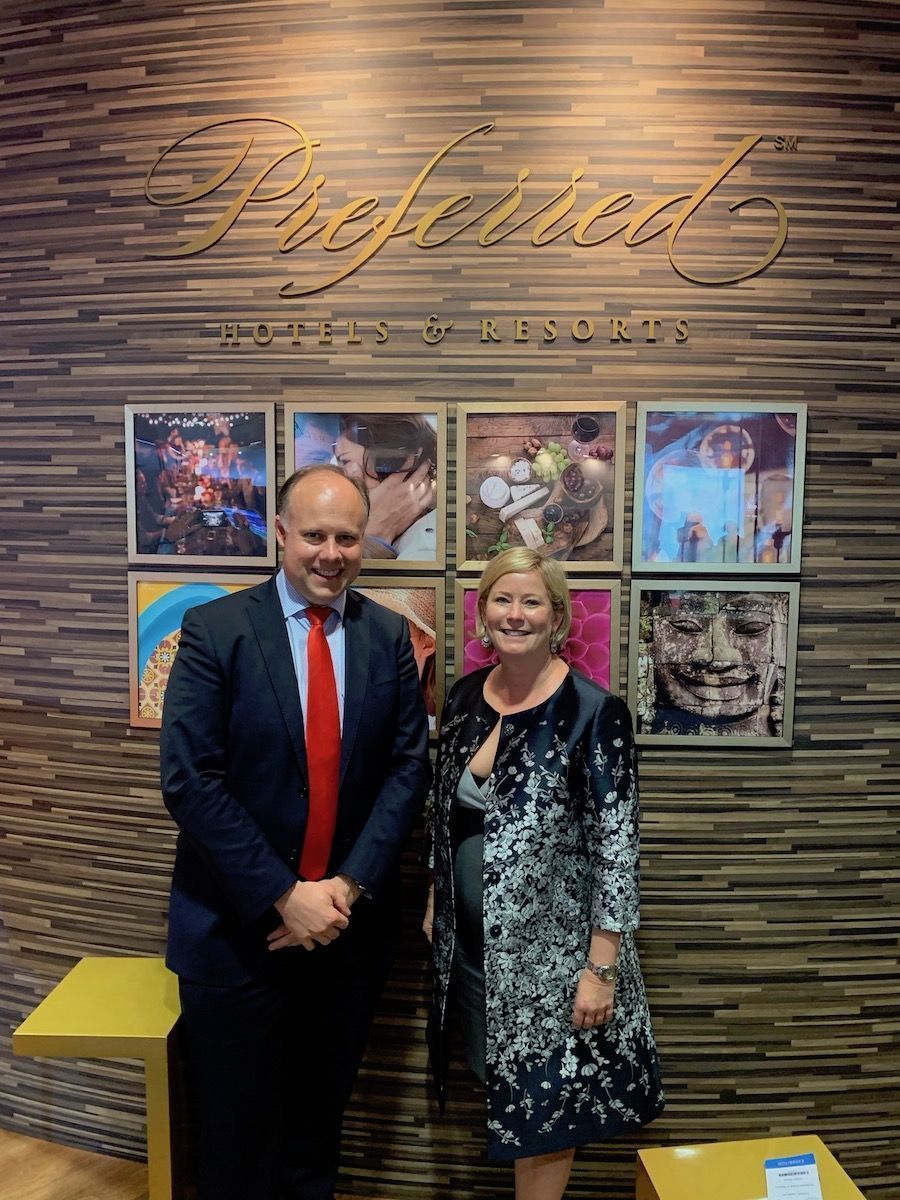 Laurent Delporte and Lindsey Ueberroth in front of the golden Preferred Hotels & Resorts sign