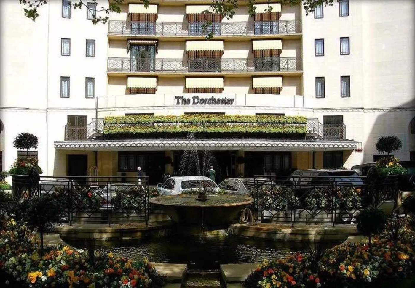 Façade du Dorchester à Londres, fontaine et massifs fleuris devant l'auvent de l'entrée principale